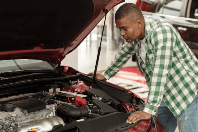 man checking under the bonnet of car